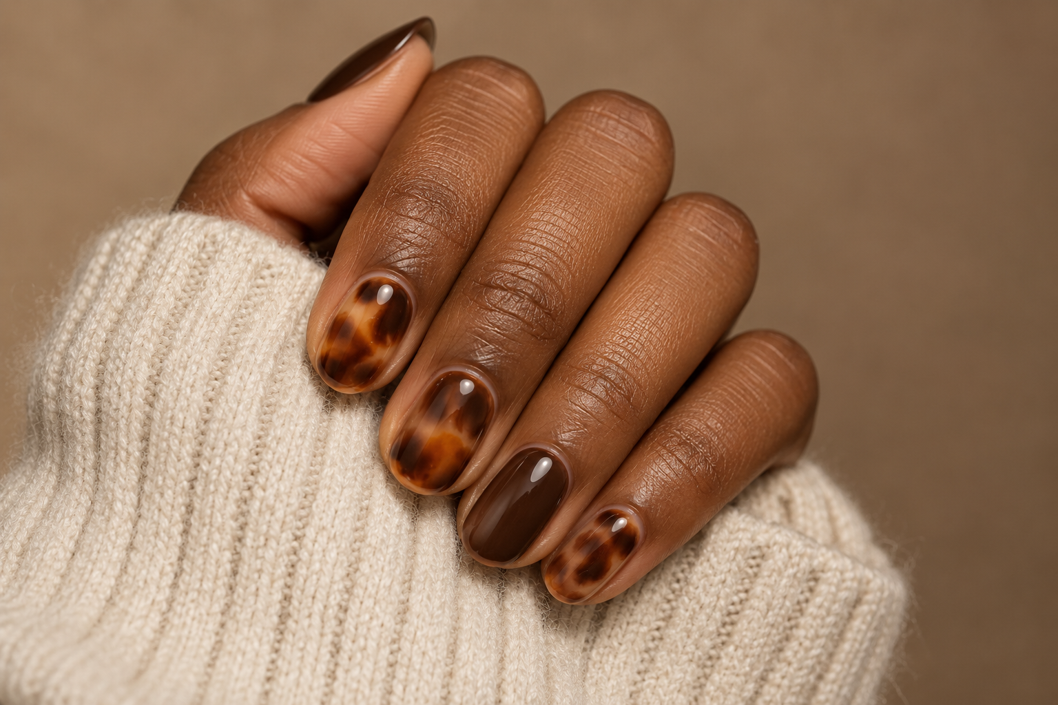 Caramel tortoiseshell manicure styling with chocolate accent nails and cream knitwear