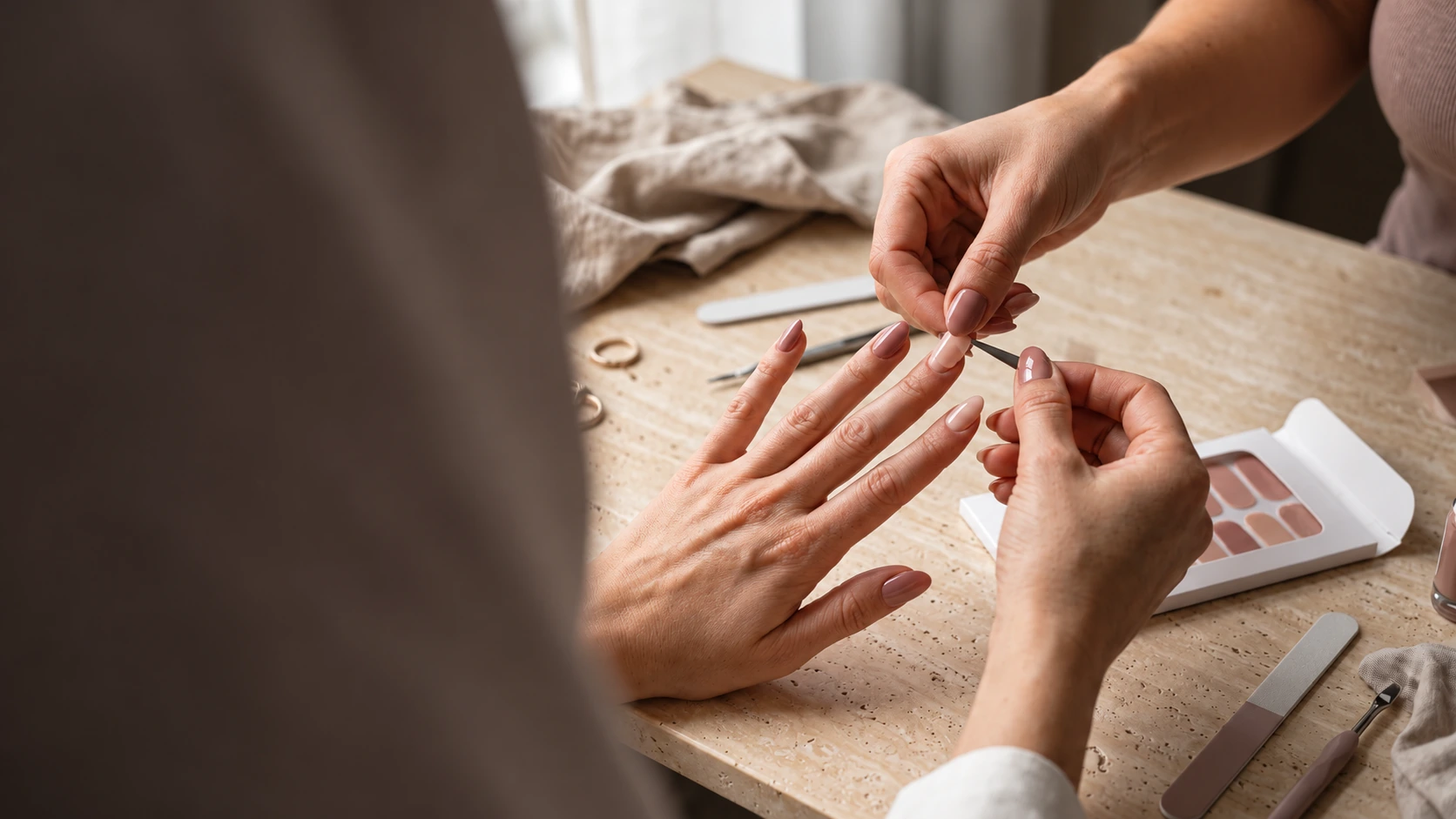 AI editorial illustration of a nude-pink manicure being carefully applied at a warm stone table